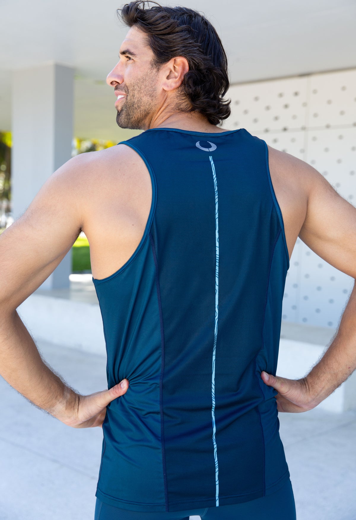 back view of man in dark blue training tank with light blue vertical line on back